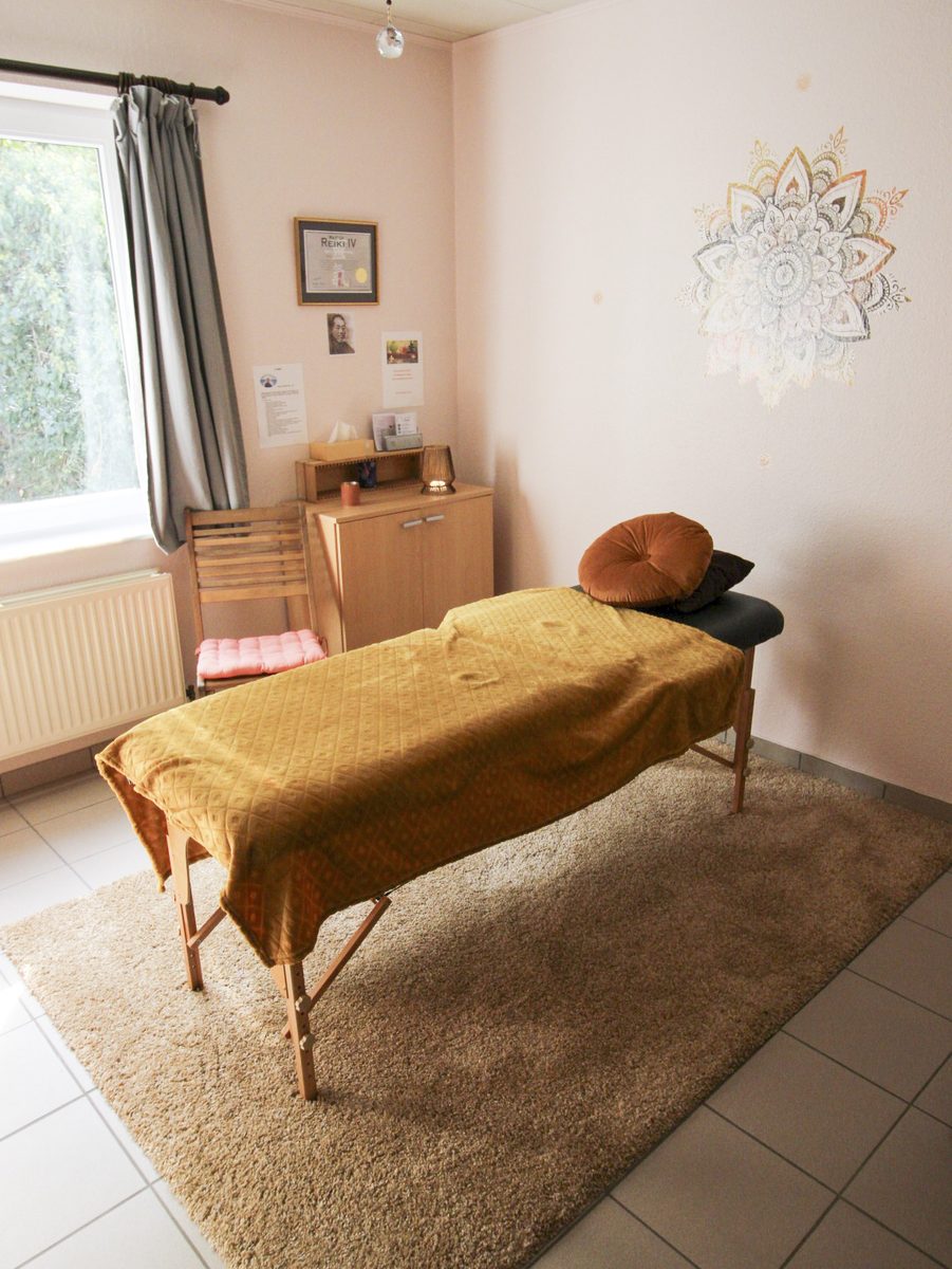 Espace de soins Reiki à Dinant : table de soin sur un tapis doux, fenêtre ouverte sur la verdure et mandala doré au mur