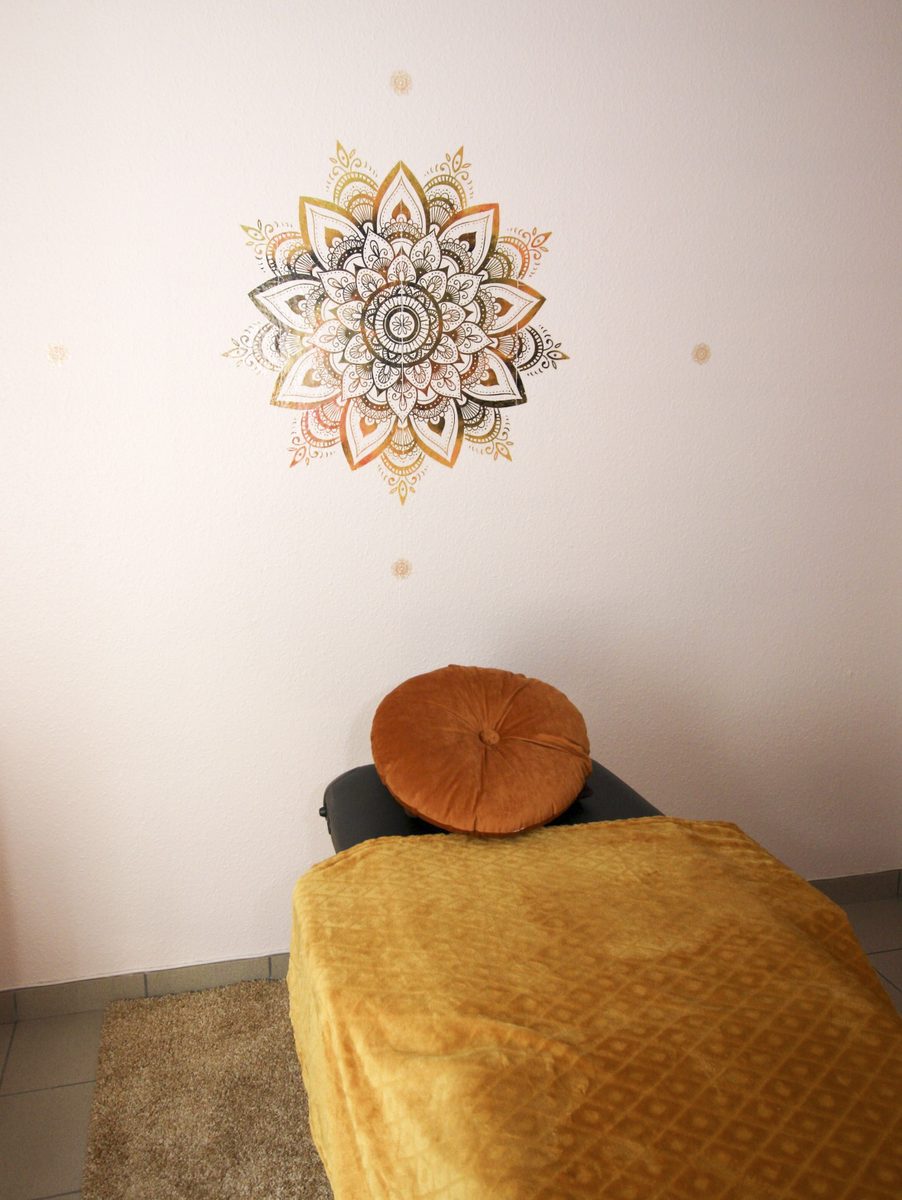 Coussin rond en velours sur la table de soin, face au mandala doré